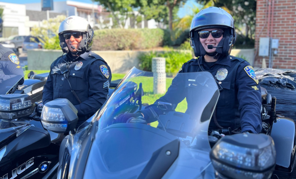Two police officers on motorcycles wearing helmets and sunglasses